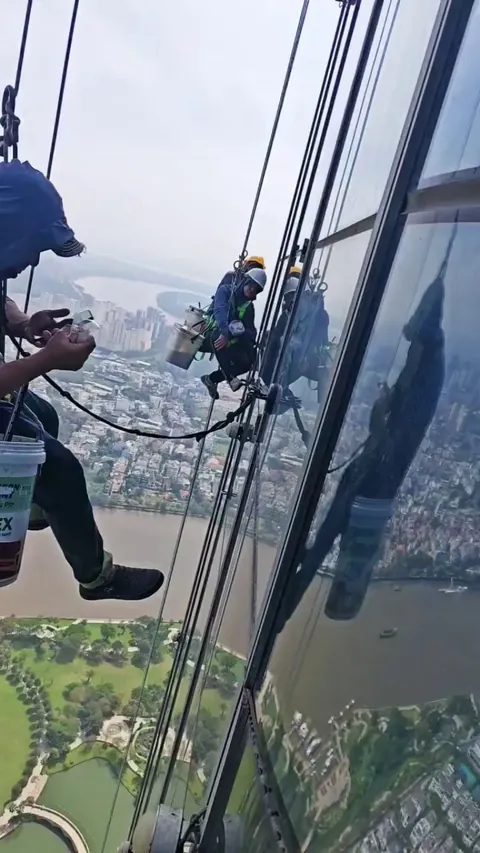 Window cleaners having breakfast and watching Tiktok while dangling outside of the tallest skyscraper in Vietnam