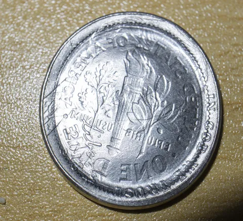 A dime imprinted into a nickel by a train wheel