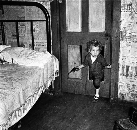 Coal miner's child using a hole in the door to enter a bedroom ,1938