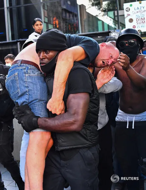In London today, a BLM protestor carries a far-right counter-protestor to get medical help.