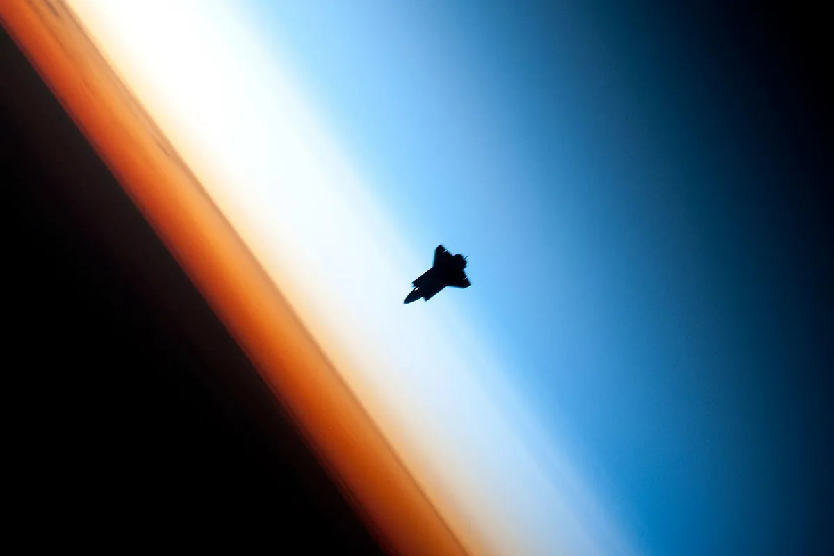 Space shuttle silhouetted in the Earth’s atmosphere