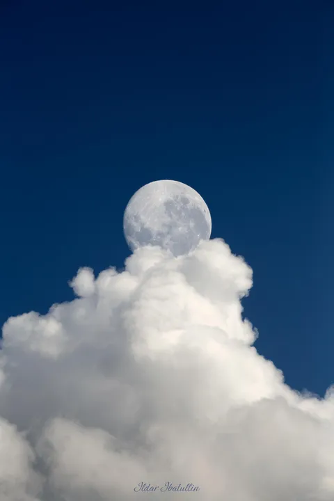 The daytime Moon hiding behind a cloud 