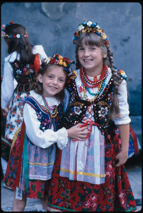 2 girls from Krakow, Polonia smile for the camera dressed on their traditional clothes, 1983. Kodachrome shot.