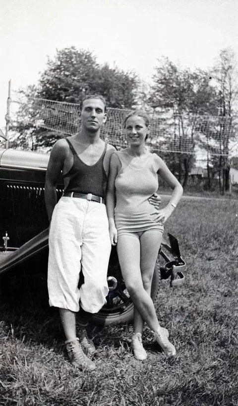 Couple posing with their car close to a badminton net, early 1920s.