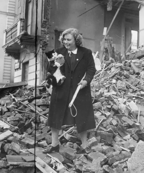 1940: "Miss Iris Davis, a 19-year old from Clapham, London recovering cats with the aid of a 'lasso' from the debris of bombed house. So far she has rescued 600 feline strays."