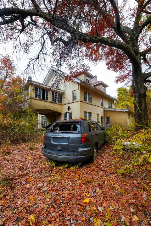 Abandoned mansion deep in the woods with a car left behind