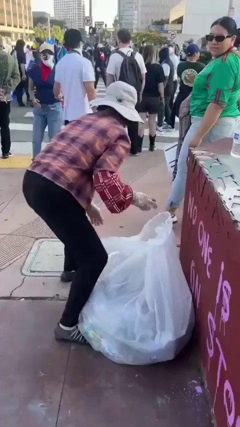 The elderly woman is doing her best to clean up sidewalk during chaos in Los Angeles