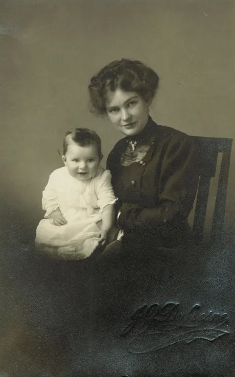 Mother gives a nice raised eyebrown and smirk while showing her baby, 1910s