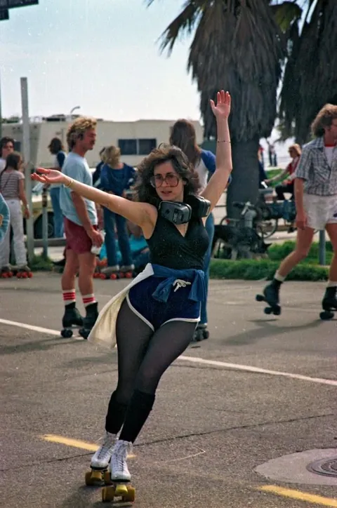 Venice Beach California during the late 1970s roller skate craze. Still has some 70s vibe but you can feel the 80s coming.