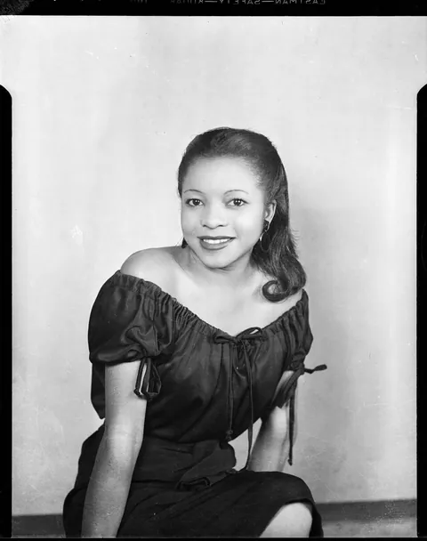 Young lady smiles for her professional studio photo, circa 1940s.