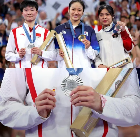 Chinese shuttler He Bingjiao carries Spanish flag badge onto the podium after her Spanish semifinal opponent’s withdrawal due to injury