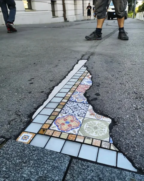 French Artist “EmEmEm”paves cracks and holes with mosaics. This is also known as “Flacking”.