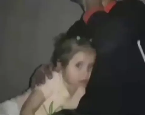 A parent covering their young child's ears as U.S. air strikes land in the background only what can be shown