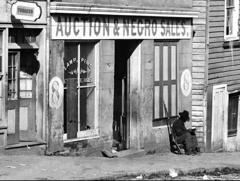 An African-American soldier sits on guard outside a slave auction. Atlanta, Georgia, 1864