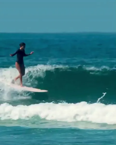 This woman surfing a small wave all the way to shore, walking the board, hanging ten, just smooth.