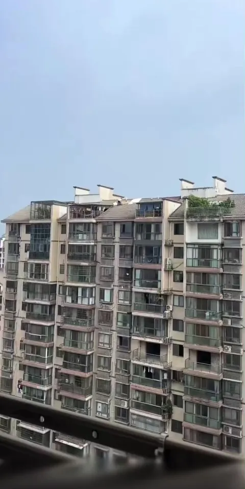 A woman drying laundry on a sloped roof 15 stories up