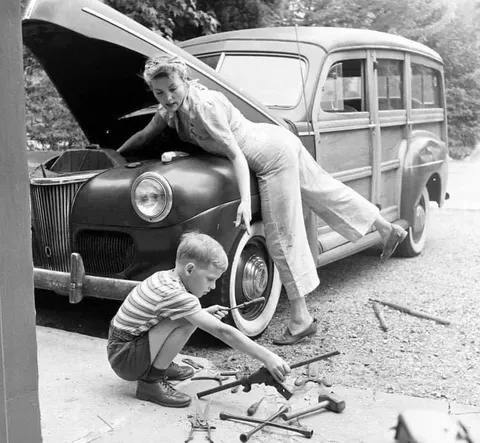 A mother repairs the family car while her husband is away at war, 1944.