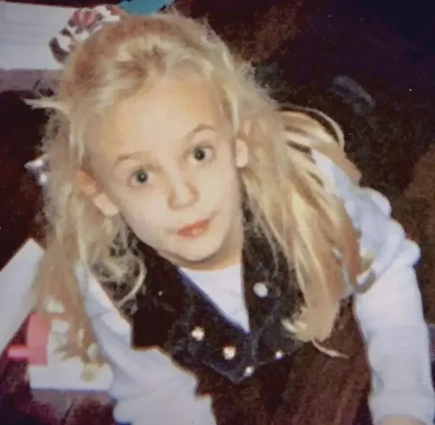 The last known photo of JonBenét Ramsey was taken at a Christmas party on December 25, 1996, in Boulder, Colorado. By the next morning, she was found dead in the basement of her home.