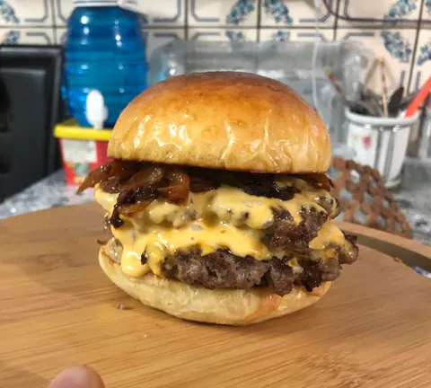 Double smashed cheese burger in a homemade brioche bun with cheddar cheese and caramelized onions