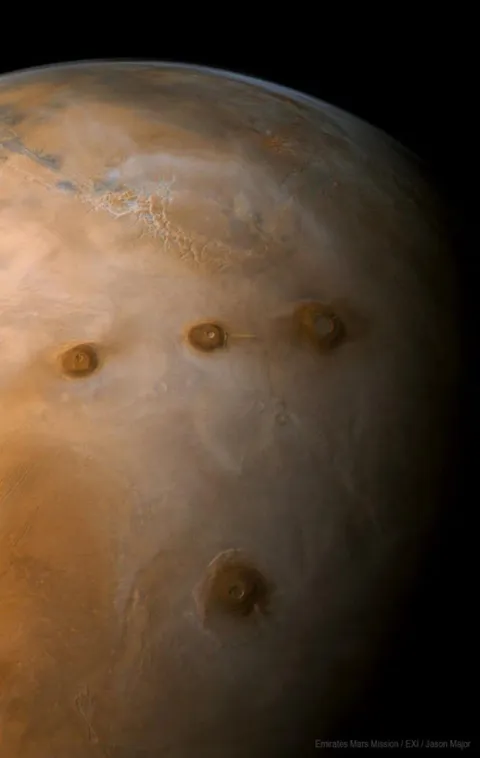Volcanic plateau Tharsis on Mars. Four volcanoes are visible. The lowest one in the picture is Olympus, which is famous for its height. In the chain above Olympus, from left to right: Ascraeus Mons, Pavonis Mons, and Arsia Mons.