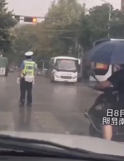A passenger saw the officer standing in the rain and tossed him an umbrella. Beautiful moment