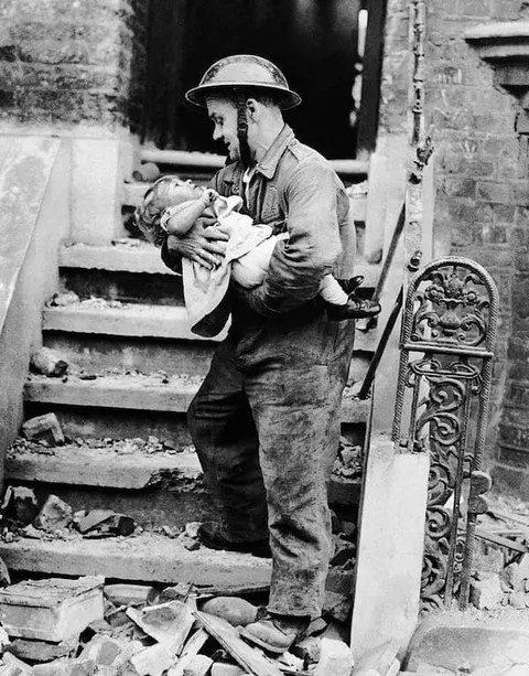 English soldier rescues a little girl  from the ruins of her home after a series of aerial bombings.  ( London  World War II, July 30, 1944)