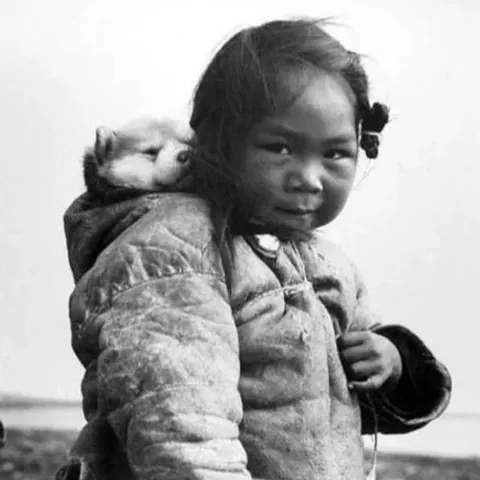 A young Inuit girl with her husky puppy, 1949