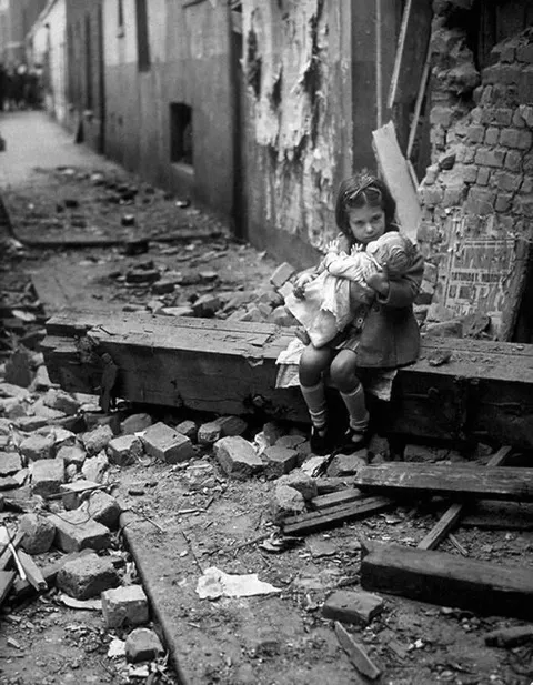London, 1940, A girl sitting in the wreckage of her bombed-out home with her doll