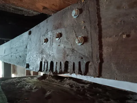 Piece of a sawmill blade used as a gusset plate to connect two beams together