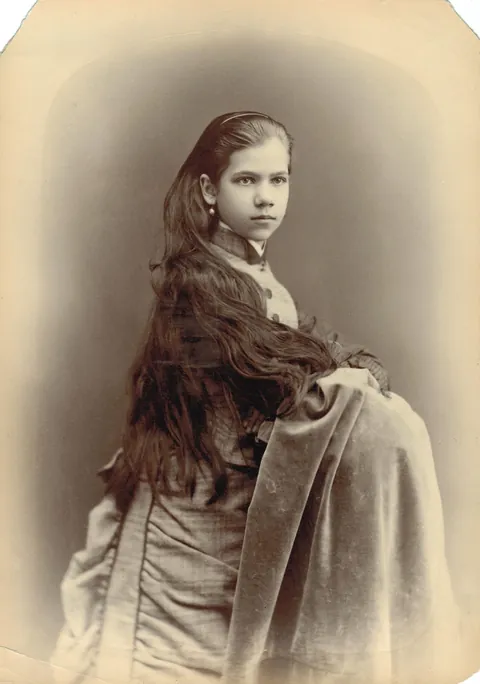 Young lady (teen?) with long hair posing with a very piercing gaze, circa 1880s. Thanks for the correction friends