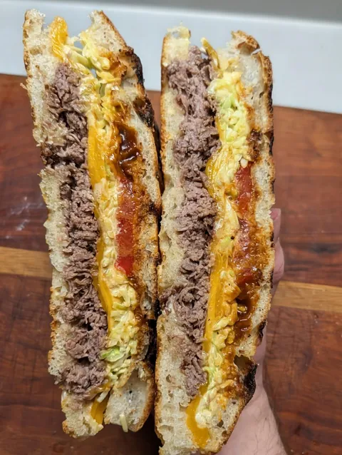 [homemade] steak, cheddar, coleslaw, tomato, Gochujang black garlic BBQ sauce on sourdough focaccia
