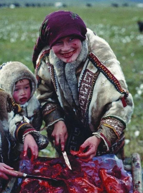 A Khanty mother and her child eating raw reindeer meat in the Yamal Peninsula (Yamalo-Nenets Autonomous Okrug), northern Siberia, Russia, 1991.