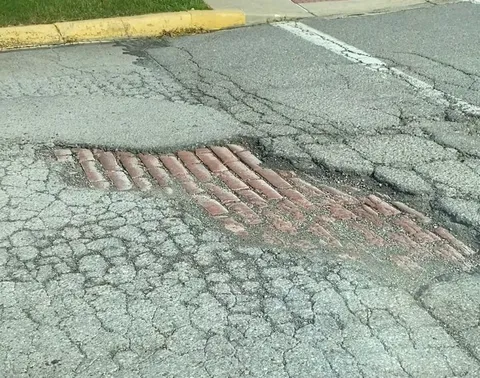 An unfixed local pothole now shows the original brick road underneath