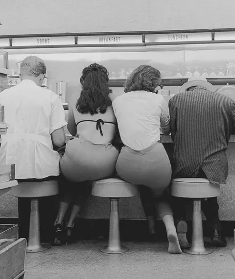 Two girls sharing a stool in Hollywood at Lee Drugs,1963.