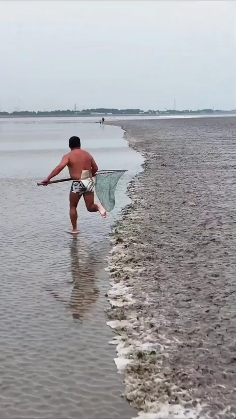 Fisherman runs at tide speed on a mirror-flat beach to reveal how the lack of reference points creates a stunning optical illusion