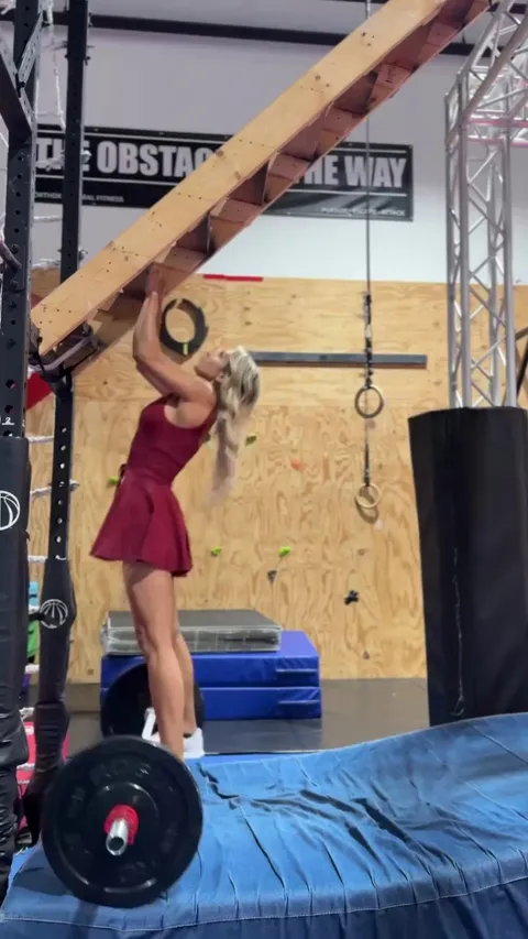 She crushes this ninja obstacle while lifting a barbell with her feet and makes it look effortless in a dress!