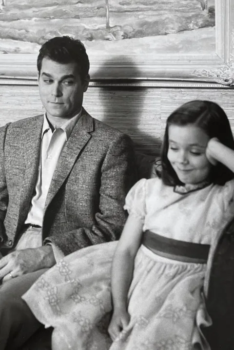 Ray Liotta and Tina Majorino, then 8, sharing mischievous smiles on the set of Corrina, Corrina (1994). Tina paid a heartfelt tribute to Ray saying “I never felt like I was ‘the kid’ on set,” she says. “When I would go to him with questions, he would say, ‘Well, what do you think?’”