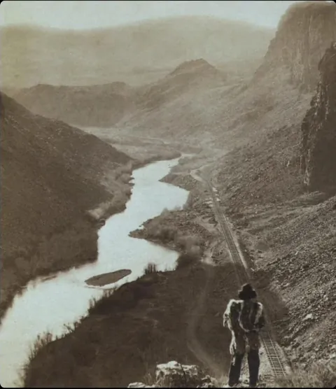 A Native American man looking at the newly completed railroad in Nevada 1867.