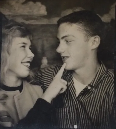 Young couple smiling to each other in the photobooth, circa 1950s.