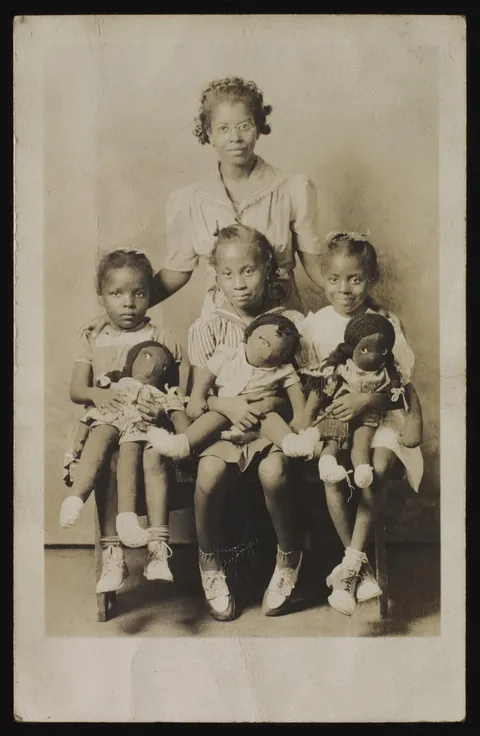 Woman and children with Black cloth dolls, 1942. Gelatin silver print. Deborah Neff Collection
