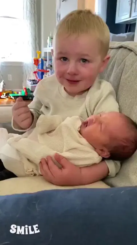 Brother cries while holding his newborn baby sister for the first time