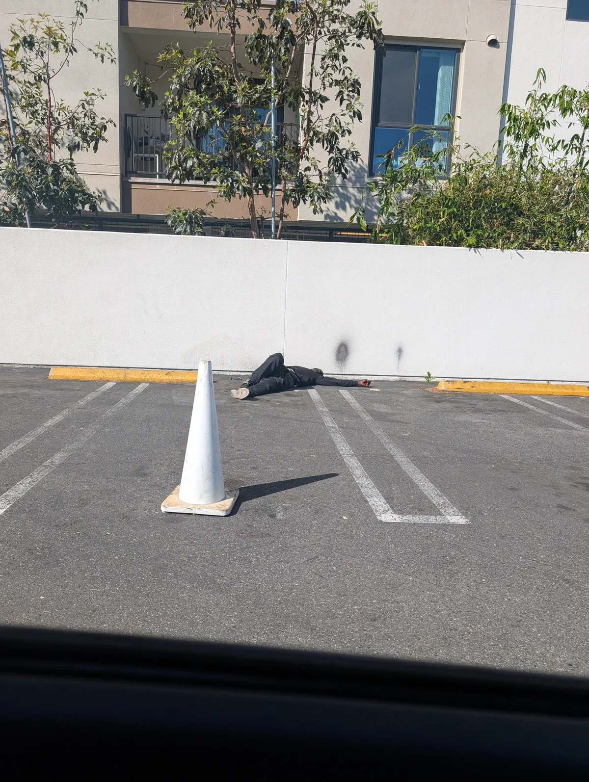 Someone put a cone to protect the sleeping homeless man in the gym parking lot