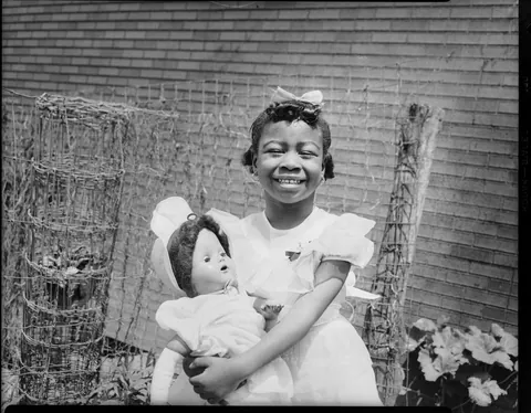 Little girl gives a bright smile with her doll (could be a gift from her mother in the second photo, Circa 1950s Kodak safety film.