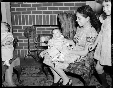 Little chubby baby and her mother posing thogether in the living room, circa 1940s. Agfa Safety film.