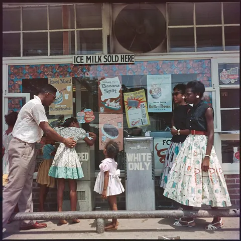 Gentleman helps little girls reach the fountain for them, in Alabama, 1956, kodachrome shot.