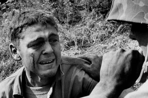Wounded when a mine blew up his Jeep, an ambulance driver sobbed by the side of the road after learning that a friend was killed in the blast, Korea 1950.