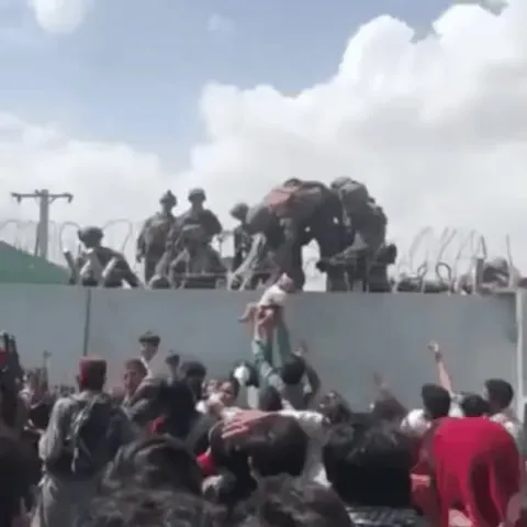 Desperate Afghan man hands baby to U.S. Soldier at the perimeter wall of the airport in Kabul