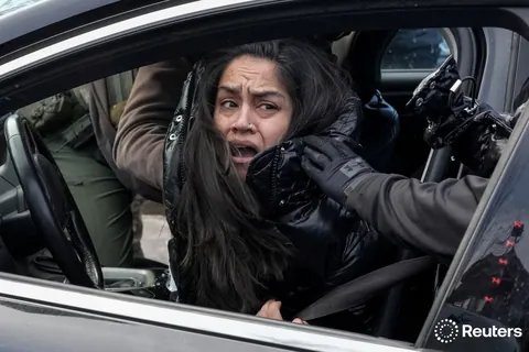 Federal agents grab a woman to drag her away from her car, Minneapolis, Minnesota, January 13, 2026.