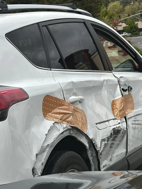 Giant Band-aid stickers on this smashed up car (OC)