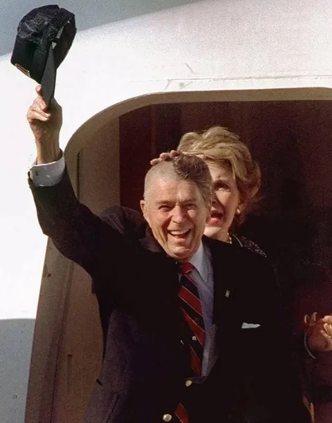 Ronald Reagan doffs his baseball cap, exposing his partially shaved head before the applause of well wishers who saw him off at the airport in Rochester, Minn., Sept. 15, 1989. He had recently undergone skull surgery.